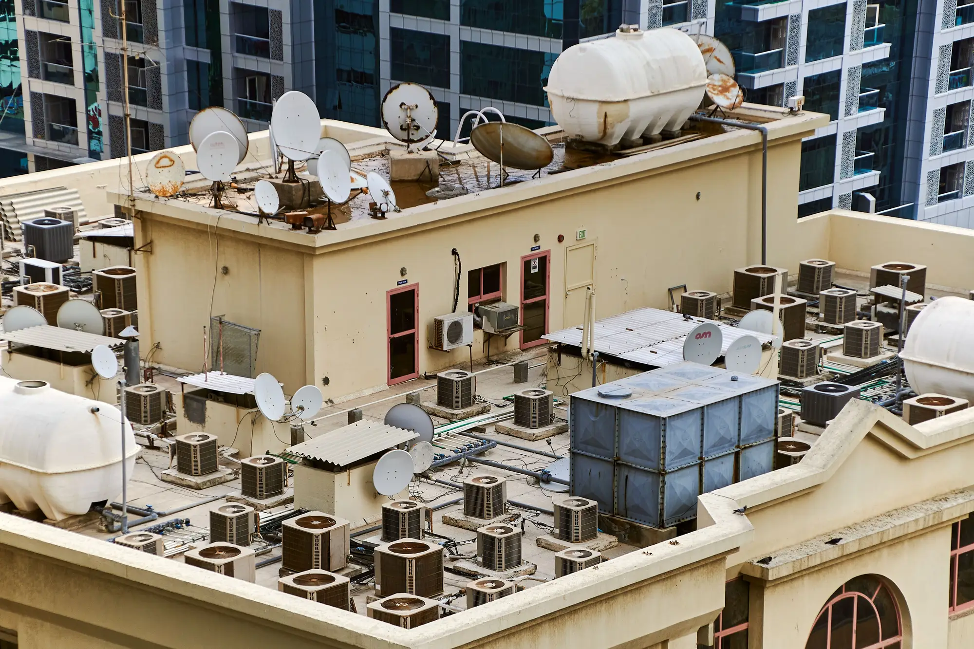 A flat roof crowded with air-conditioning units, water tanks and satellite dishes